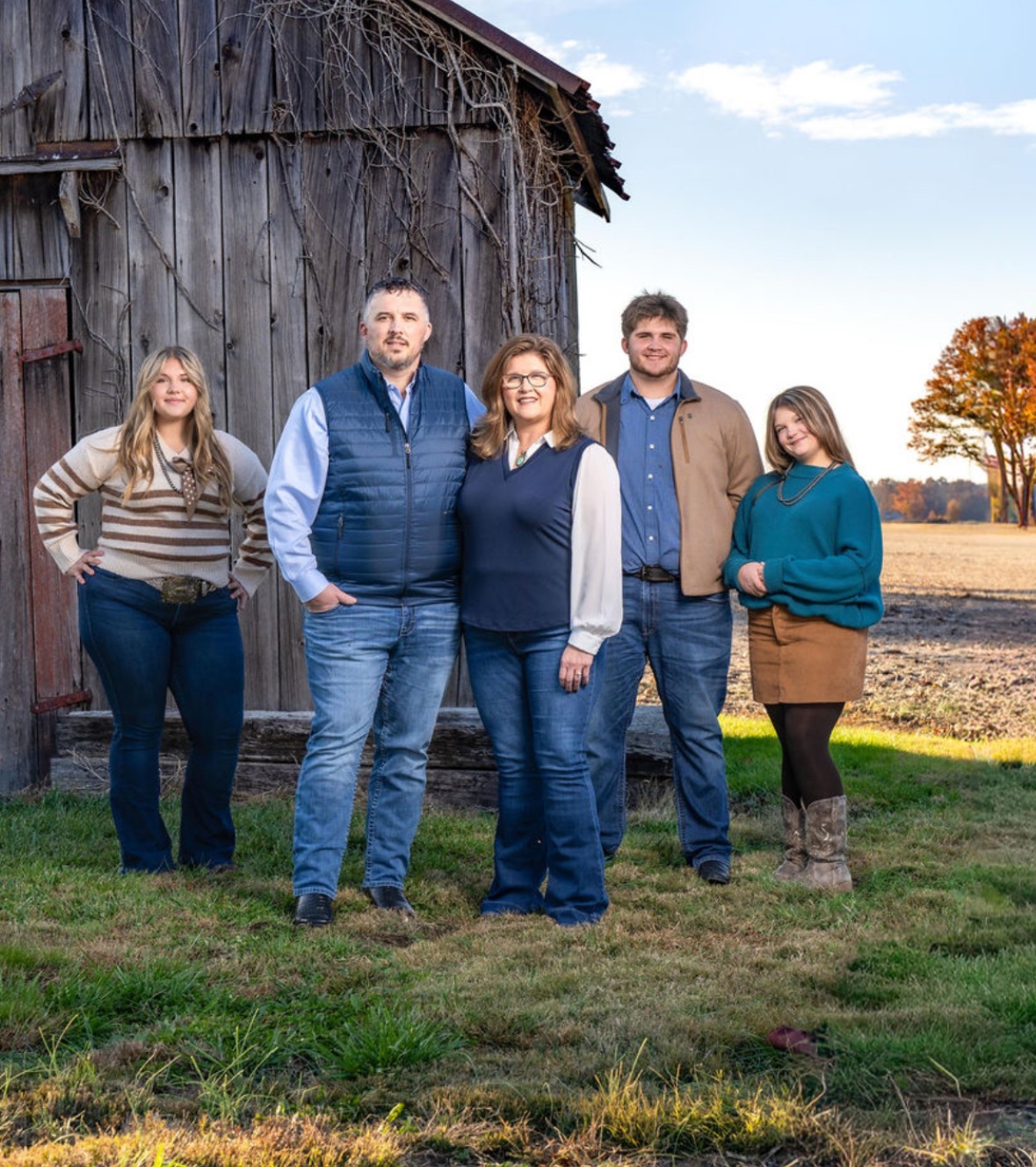 The Wilhelmy family of five—Sadie, Brad, Kristi, Aiden, and Olivia—standing together in front of their barn