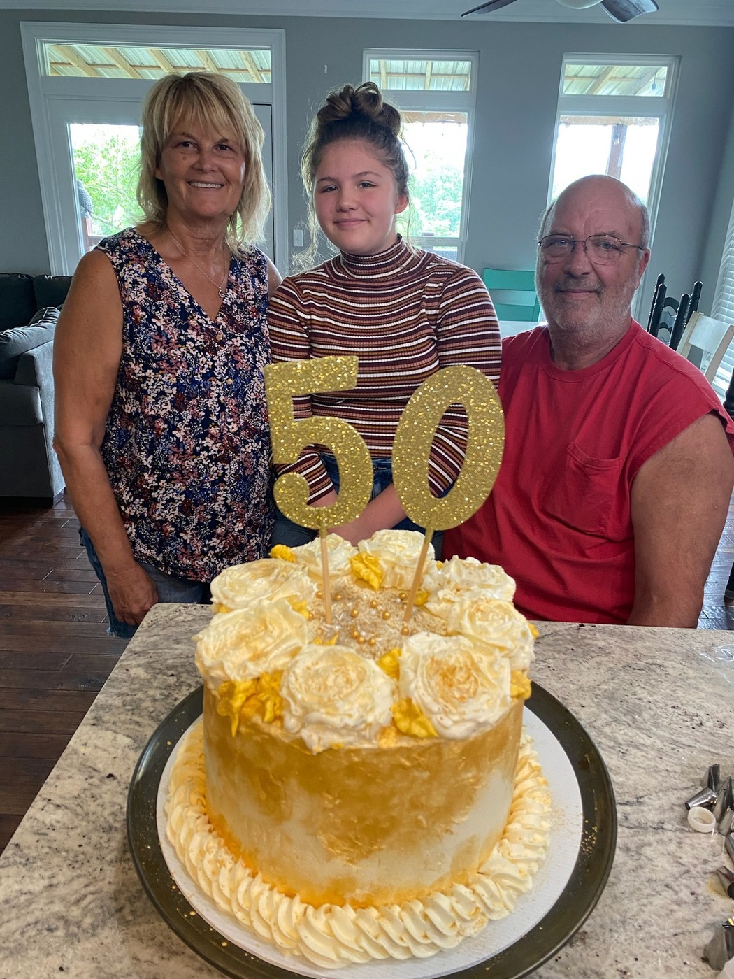 Gold and cream anniversary cake with piped roses, gold pearls, and 50 topper