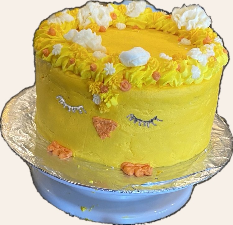 Yellow sleeping chick shaped cake with closed eyes and soft buttercream feathers