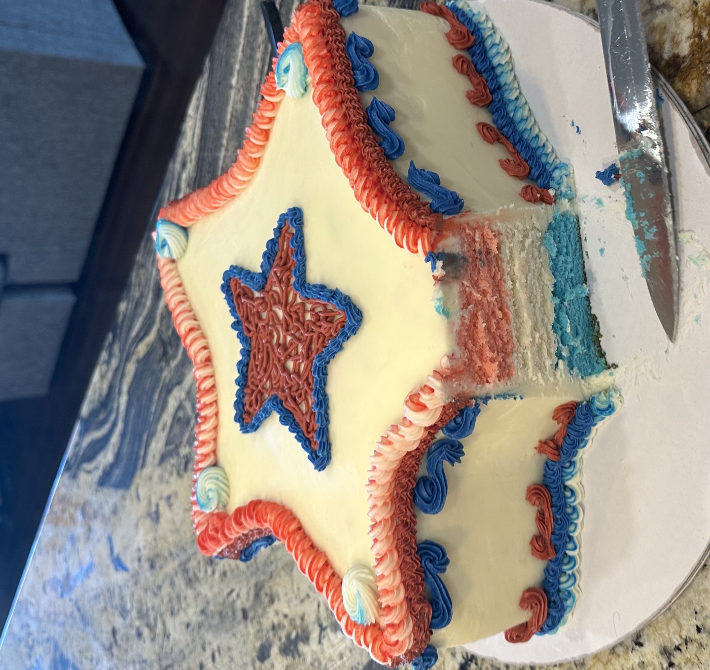 Star-shaped red white and blue cake with striped interior layers visible